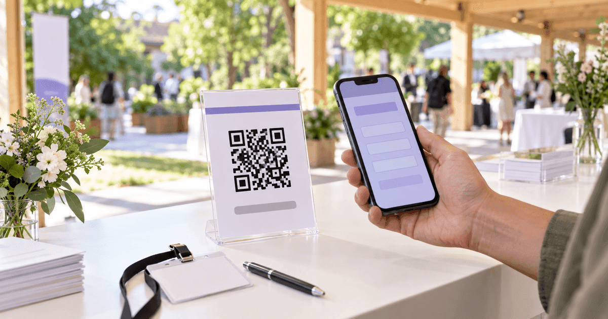 A printed event flyer with a QR code and the words Scan to RSVP standing on a wooden table, a phone held above it showing a form on screen